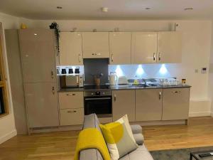 cocina con armarios blancos y sala de estar con sofá en Inviting 2-Bed Apartment in Reading en Reading