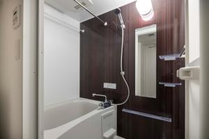 a bathroom with a bath tub and a mirror at Quador Waseda in Tokyo