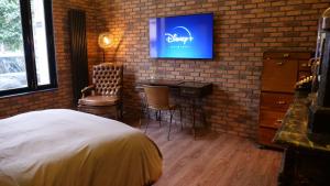 a bedroom with a desk and a tv on a brick wall at 35 SPEAKEASY - Ambiance PUB Anglais Centre Ville avec Parking in Reims