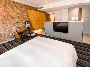 a bedroom with a large white bed and a kitchen at Guide Education Culture Hotel Kaohsiung Museum of Fine Arts in Kaohsiung