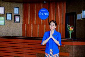 Hotel Dafam Pekalongan في بيكالونغان: امرأة تقف في غرفة بيديها على وجهها