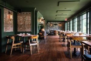 a dining room with tables and chairs and windows at The New London Inn in New London