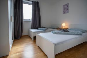 two beds in a room with a window at NEW East Side Apartment Innsbruck I Free Parking in Innsbruck