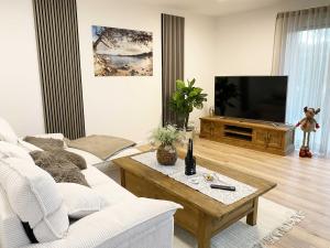 ein Wohnzimmer mit einem weißen Sofa und einem TV in der Unterkunft Wiedbachtaljuwel in Roßbach