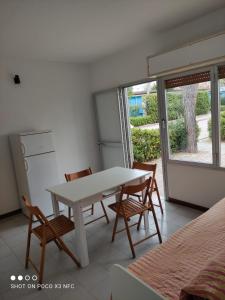Villaggio Welcome Riviera d'Abruzzo في تورتوريتو ليدو: طاولة بيضاء وكراسي في غرفة مع نافذة