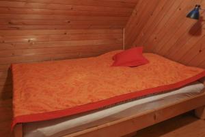 Cama en habitación de madera con almohada roja en Pravlca (Fairytale Cottage), en Zgornje Gorje