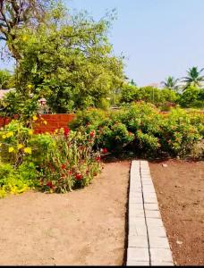 a garden with colorful flowers and a brick path at Scarlet Resort Alibag in Alibaug