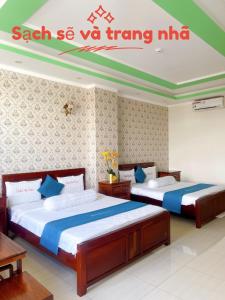 Anh Tuấn Hotel & Coffee - Pleiku, Gia Lai في بلاي كو: سريرين في غرفة نوم مع علامة على الحائط