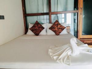 a white bed with three pillows on it at Hakuna Matara Beach Bungalows in Matara