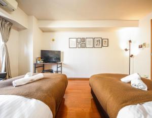 ein Hotelzimmer mit 2 Betten und einem TV in der Unterkunft Lite House Shinsaibashi V in Osaka