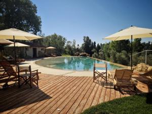 een terras met stoelen en parasols naast een zwembad bij Agriturismo Ai Massi in Casale Marittimo