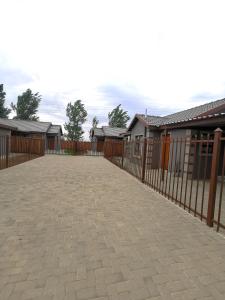a fence with a brick driveway in front of some houses at MV self-catering - Rooms in Bloemfontein