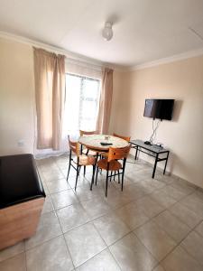 a dining room with a table and chairs and a television at MV self-catering - Rooms in Bloemfontein