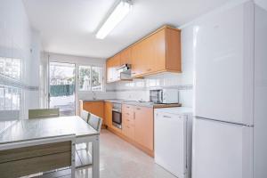 Una cocina con gabinetes de madera y un refrigerador blanco. en Estrella Coral 12A, en Alcudia