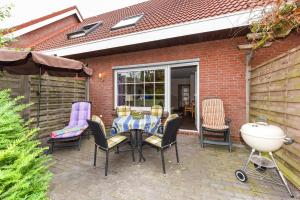 カロリーネンジールにあるFerienhaus Sonnyのパティオ(テーブル、椅子、パラソル付)