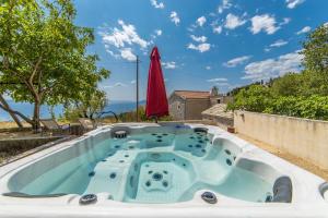 a hot tub in the backyard with a red umbrella at Holiday home Fetiva Makar in Makarska