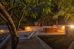 a table and a chair under a tree at night at Holiday home Fetiva Makar in Makarska