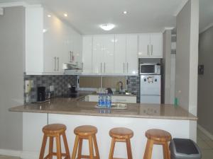 una cocina con encimera y taburetes. en Modern Comfy 2-Bedroom Self-catering Apartment - 1 minute walk to Strand beach en Strand