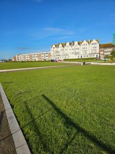 a long shadow of a building on a grass field at The Margaret Residence in Bexhill