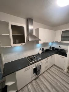 una cocina con armarios blancos y encimeras negras en a two bedroom cosy hideaway based in greenwich, en Londres
