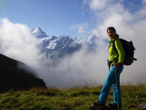 Una mujer con una mochila parada en la cima de una montaña en Hotel Lauberhorn - Home for Outdoor Activities, en Grindelwald