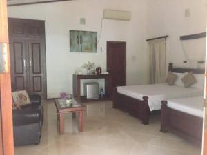 a bedroom with a bed and a couch and a table at Hemamala Bungalow in Anuradhapura