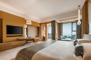 Habitación de hotel con cama grande y TV en Huidong Regal Palace Resort, en Huidong