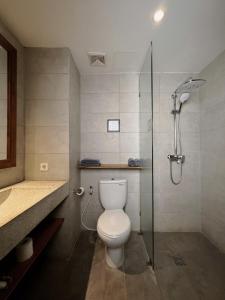 uma casa de banho com um WC e uma cabina de duche em vidro. em Surf Motel em Canggu