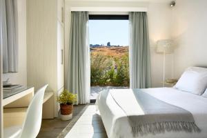 una camera con un letto e una grande finestra di Eleia Seafront Rooms & Villas a Pétra