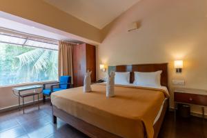 una camera d'albergo con un grande letto e una finestra di Sunshine Resort Calangute Goa a Calangute