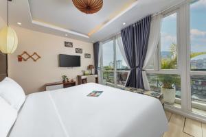 a bedroom with a large white bed and large windows at Golden Legend Diamond Hotel in Hanoi