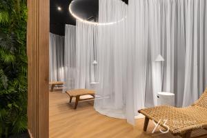 una sala de estar con cortinas blancas y una silla en Saint Martin Residence Old Town with Wellness, en Poznan