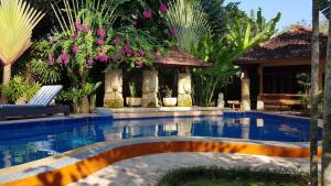 a swimming pool in a yard with flowers at Lombok Stanley Garden Villas in Montongbuwoh