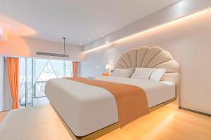 um quarto com uma grande cama branca e uma grande janela em Kunming Dianchi Mideel International Apartment - South Asian Style Fuhai Metro em Kunming