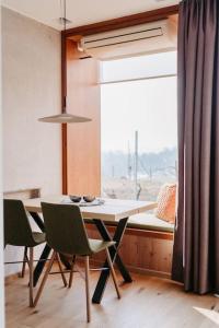 ein Esszimmer mit einem Tisch, Stühlen und einem Fenster in der Unterkunft *Relax Apartment Hochgraßnitzberg* in den südsteirischen Weinbergen in Spielfeld