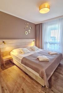 a bedroom with a large bed and a window at HolidayHomePL Bel Mare 314e z sypialnią i balkonem in Międzyzdroje