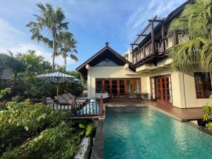 a house with a swimming pool in front of a house at Boutique hotel villa Cantik and karma beach club in Uluwatu