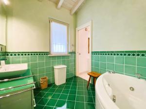 ein grün gefliestes Bad mit einer Badewanne und einem Waschbecken in der Unterkunft Villa Chiara in Polpenazze del Garda