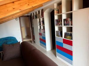 a room with a couch and a book shelf with dvds at Casa Corinaldesi in Marotta