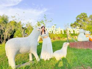 a woman is standing next to a statue of sheep at เนริสารีสอร์ท เขาค้อ in Ban Khao Ya Nua