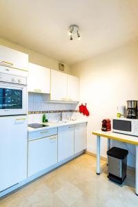 une cuisine avec des armoires blanches et une table dans l'établissement Le Gouverneur, 100m du lac avec parking, à Annecy