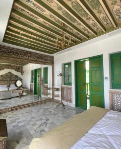 Schlafzimmer mit einem Bett und einer Decke mit grünen Türen in der Unterkunft Dar Waya in Mahdia