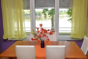 a dining room table with chairs and a vase of flowers at Guesthouse Sava in Slavonski Brod