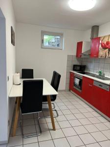una cucina con armadi rossi, tavolo e sedie di Gartenparadies Apartment in Urbar a Urbar