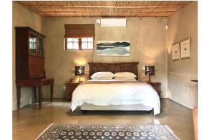 a bedroom with a bed with white sheets and a window at Blue Mountain View Cottages in Clanwilliam
