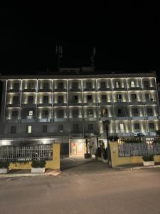 a large white building with windows at night at Hotel Vittoria in Rosarno