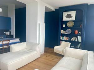 - un salon avec deux chaises blanches et un mur bleu dans l'établissement FACE MER La Baule Le Panoramique, à La Baule