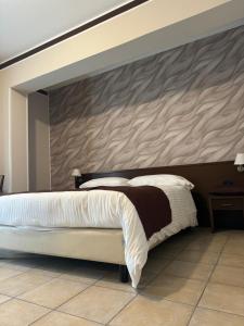 a bedroom with a large bed with a wall at Hotel Vittoria in Rosarno