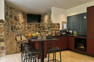 a kitchen with a stone wall and a counter with stools at Hôtel Domaine A Flatta in Calenzana