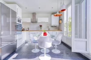 a white kitchen with a glass table and chairs at Greg & Theo's in Fontenay-sous-Bois